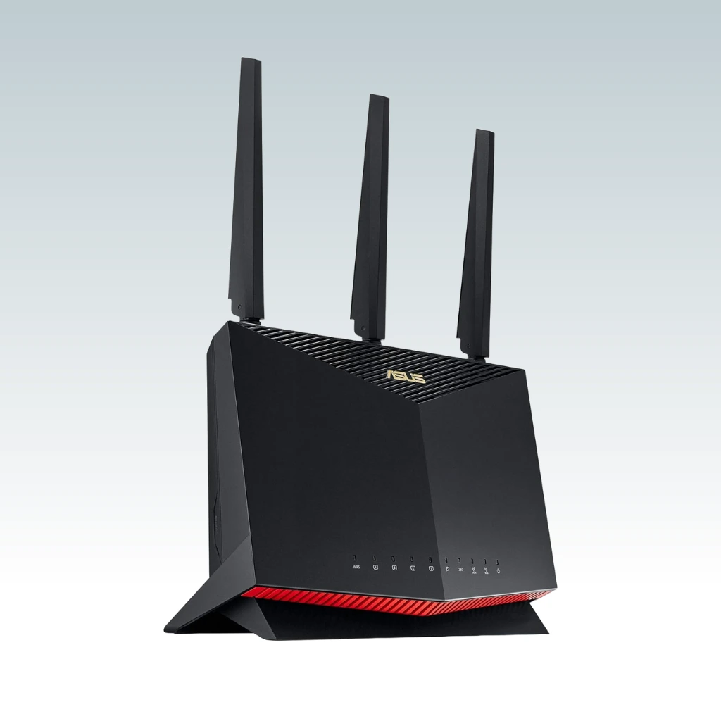 A black ASUS RT-AX86U Pro with red accents and three external antennas, placed against a light gray background.